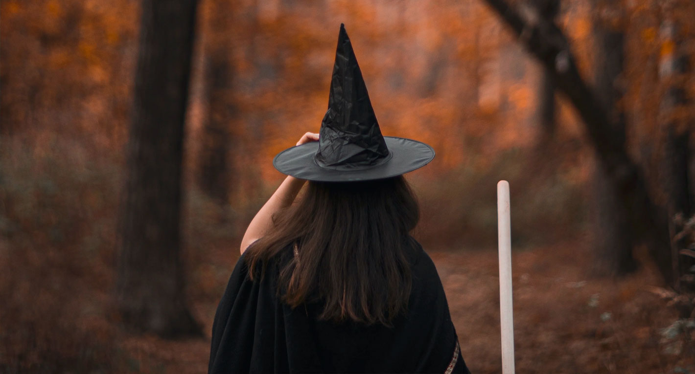 spooky young witch headed into forest fall colors halloween