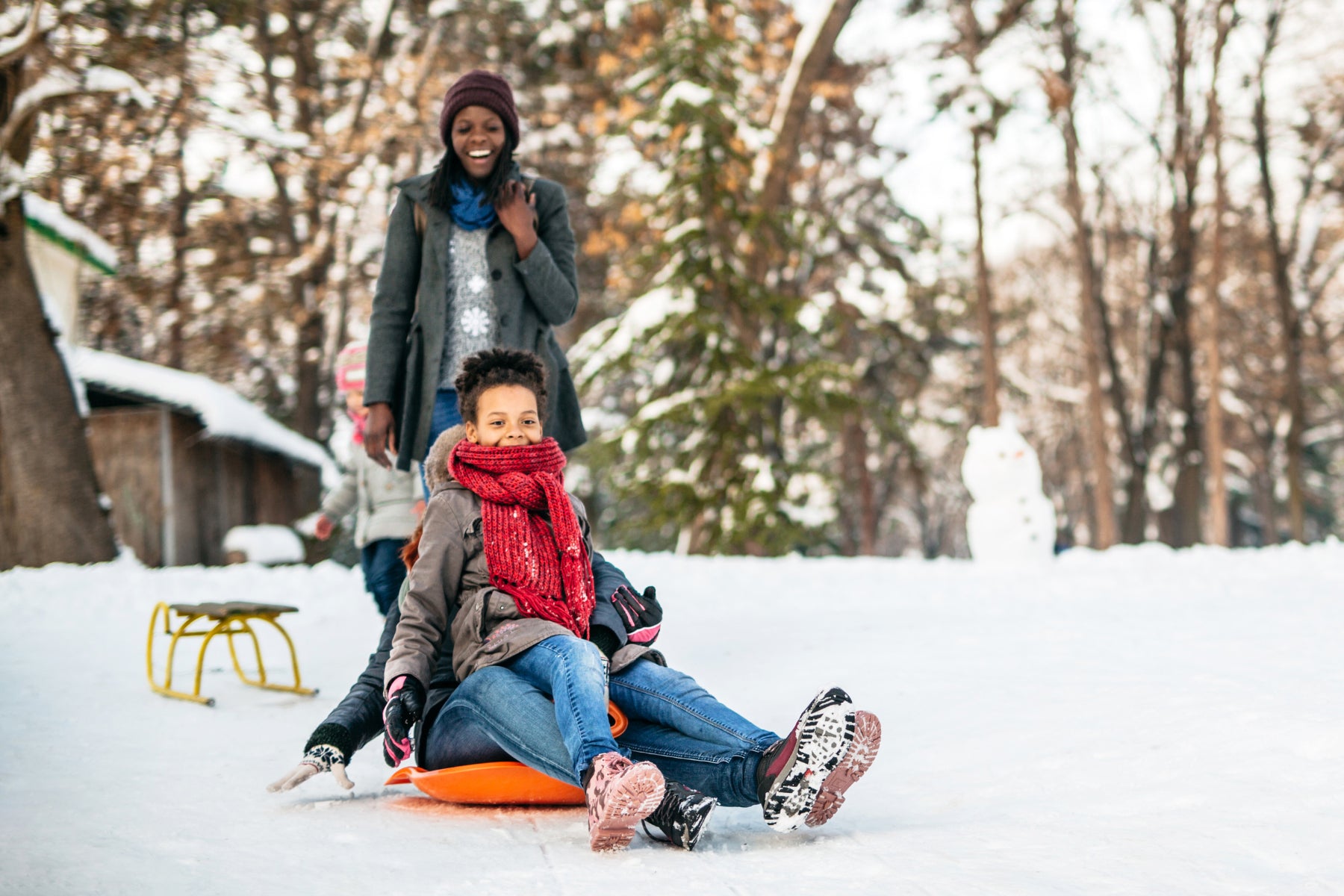 woman and child sled winter fun snow nature forest