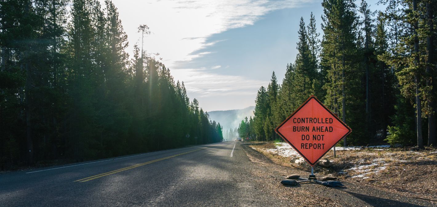 Controlled burn sign along road in forest warning motorists of a prescribed burn area ahead