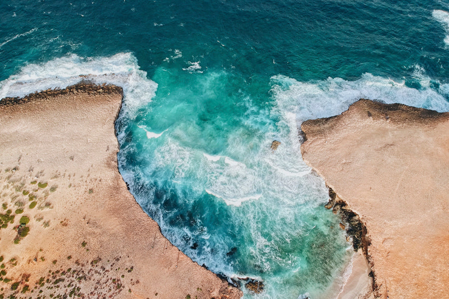 bright blue ocean waves crashing into sandy tan shoreline
