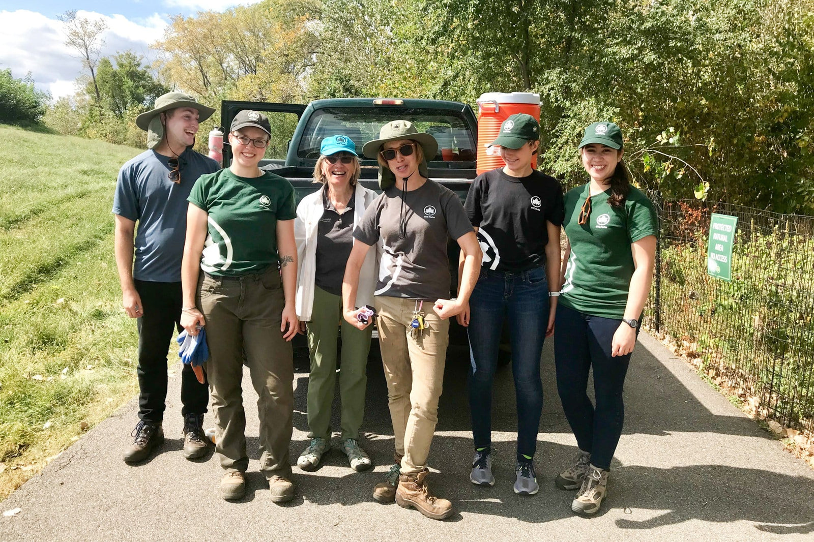 group of tree planters posing happily in front of a truck in a park