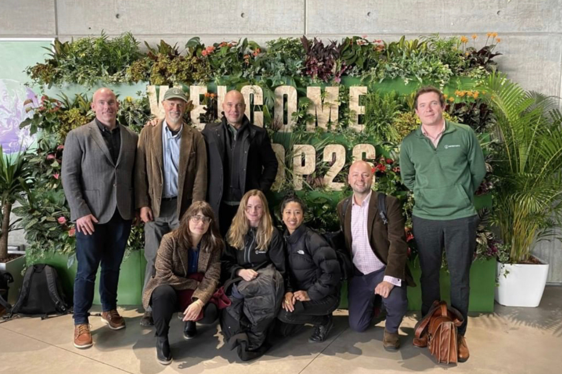 8 people standing in front of greenery at COP26