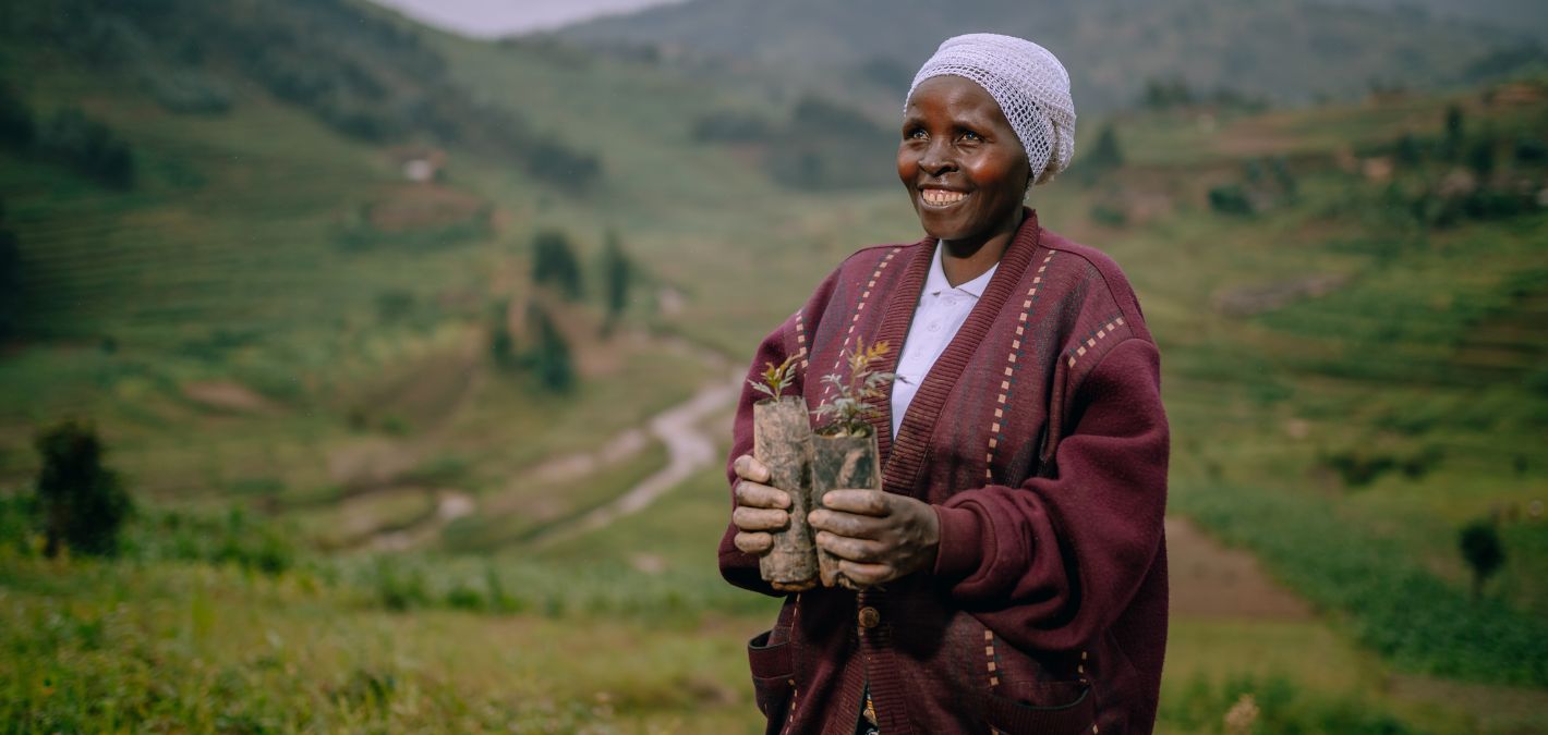 woman holding seedlings smiling rwanda