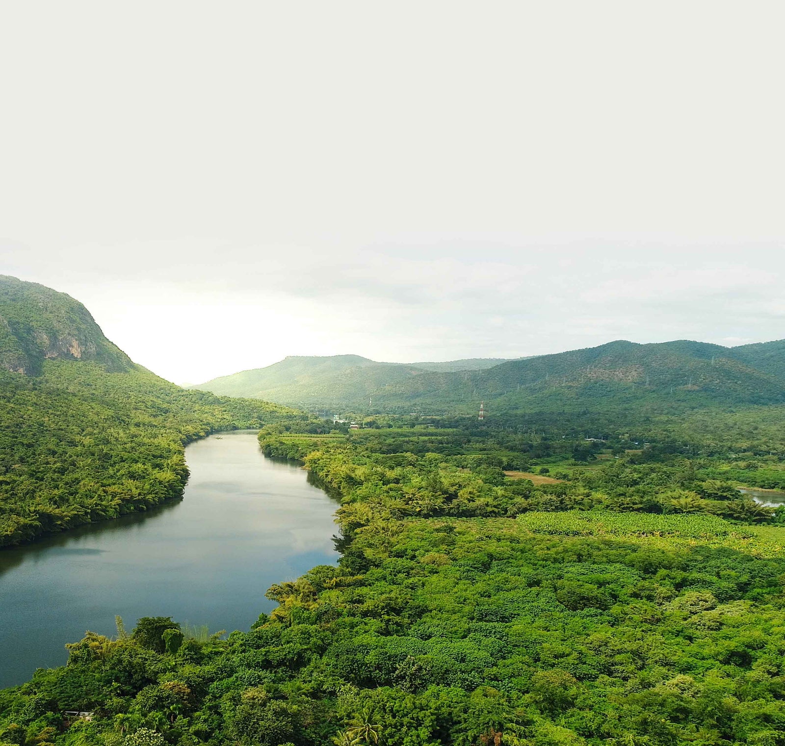 River surrounded by lush greenery and mountains under a cloudy sky