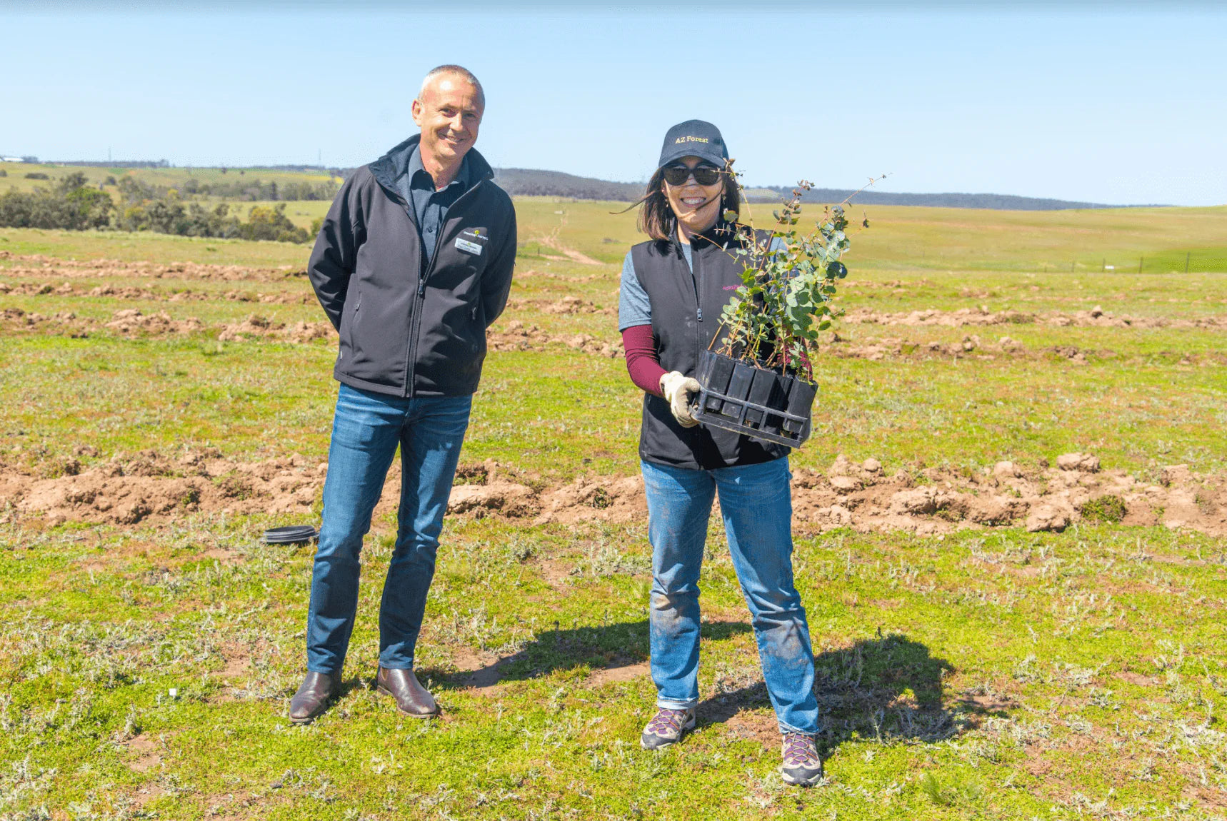 two people with seedlings at reforestation event